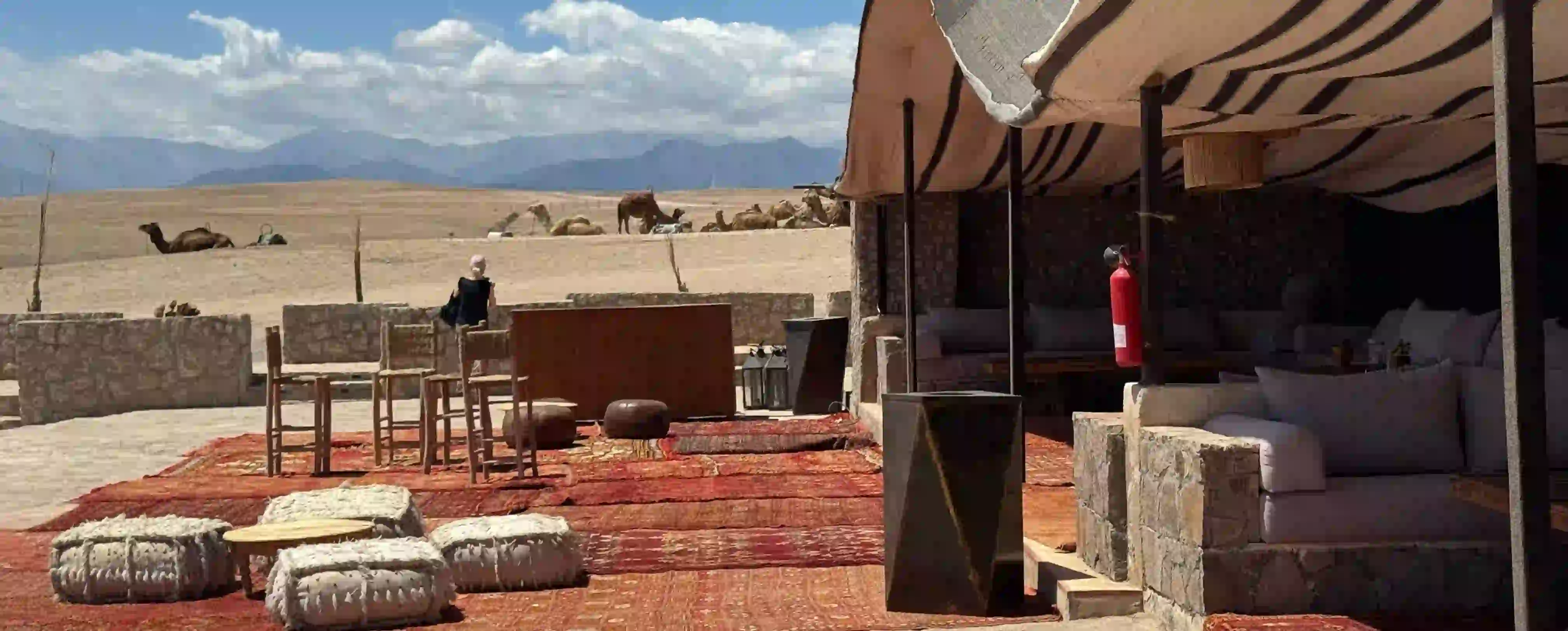 Luxury Desert Camp in Agafay Desert Luxury desert camp with camels in Agafay Desert under Atlas Mountains sunlight.