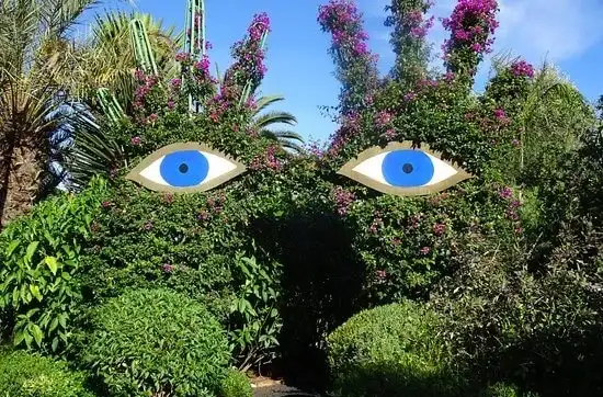 Artistic garden sculpture with iconic blue eyes hidden in lush greenery, a unique botanical scene in Marrakech